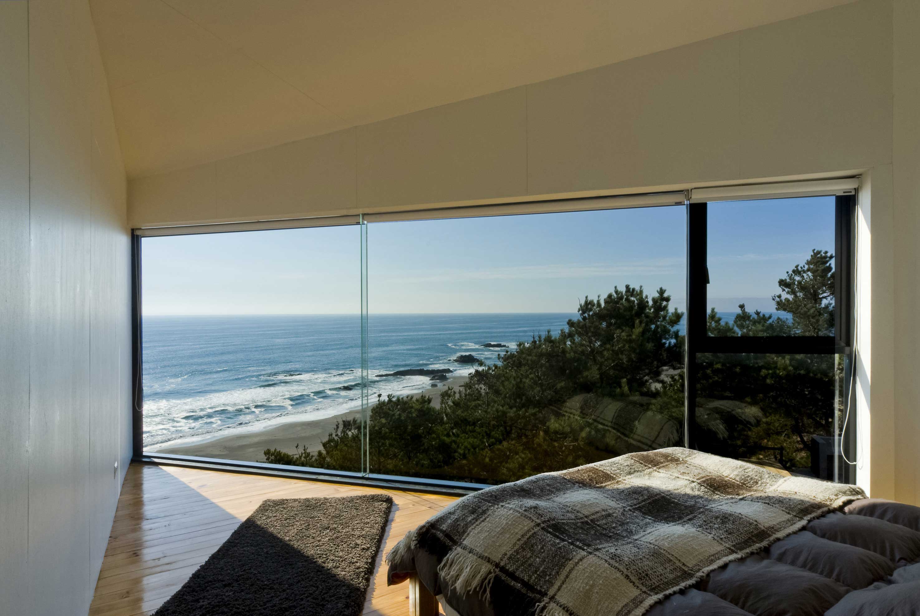 Angular Bedroom With A Floor-To-Ceiling Glass Wall And Ocean View